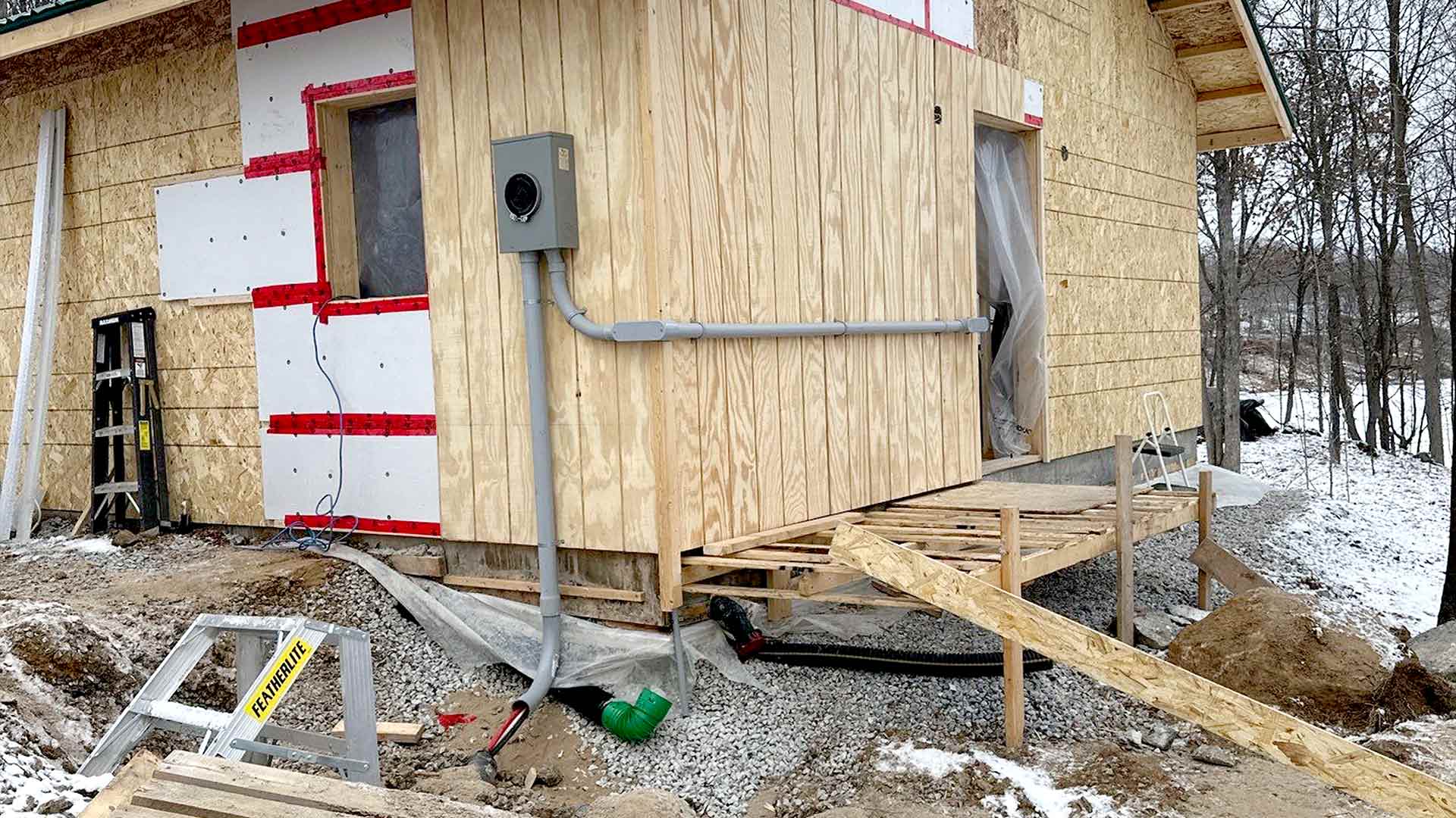 Rural new-build structure with exterior service conduit and winter site conditions